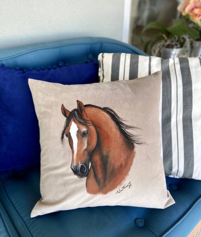 Almofada com cavalo alazão pintado à mão sobre um sofá azul