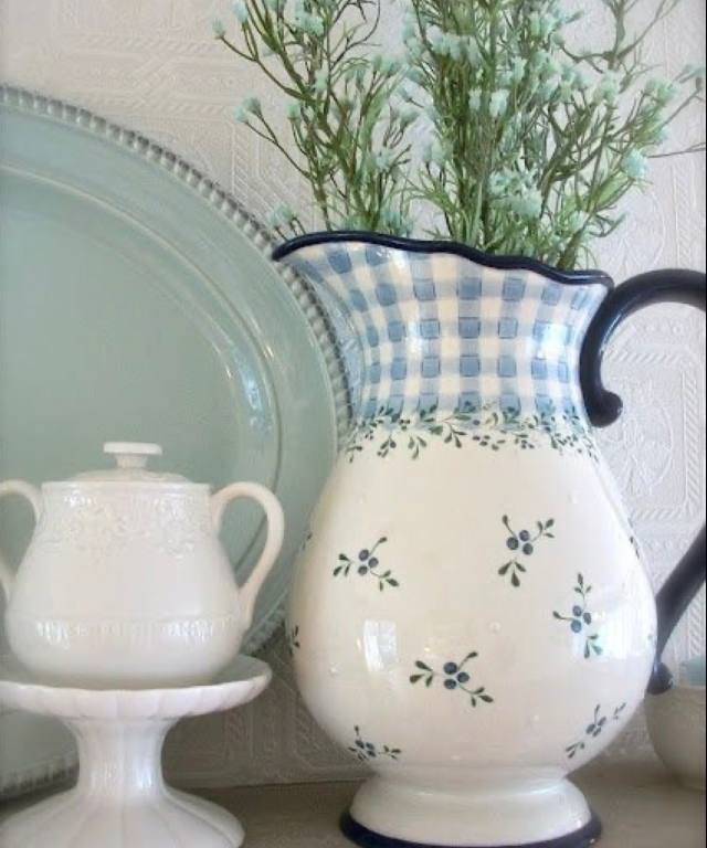 Jarra de cerâmica com xadrez azul e pequenas flores pintadas à mão, ao lado de um açucareiro branco