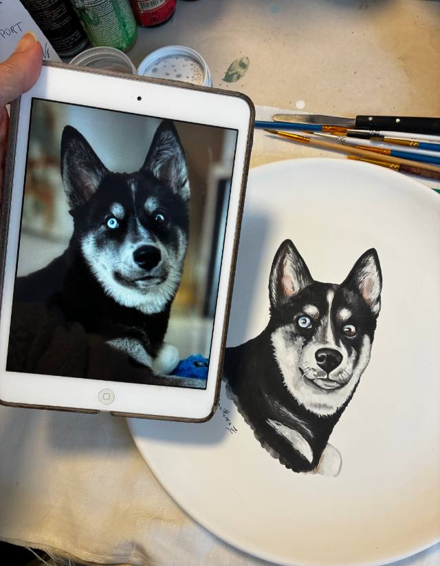 Foto de um cão husky em um tablet ao lado do retrato dele pintado à mão em prato de cerâmica