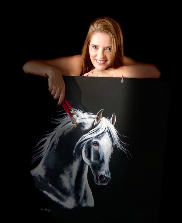 Thelma Ferraz apoiada sobre uma tela preta com cavalo tordilho pintado por ela