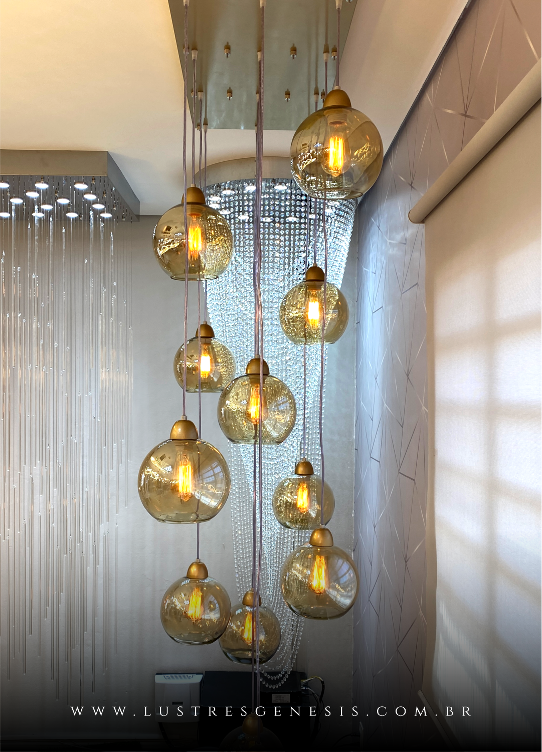 Imagem de luminárias pendentes da linha Sarvah, com várias esferas de vidro conhaque iluminadas, penduradas em um suporte moderno.