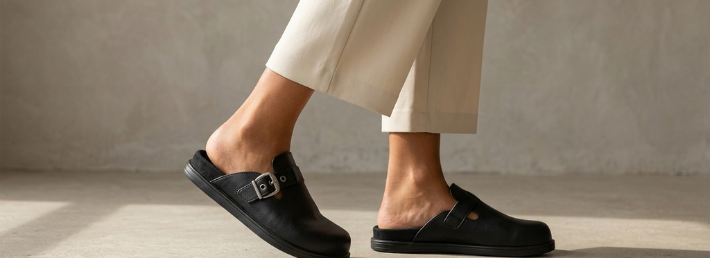 Sueco Boston en uso diario — pies con pantalón cream, paso natural sobre cemento pulido