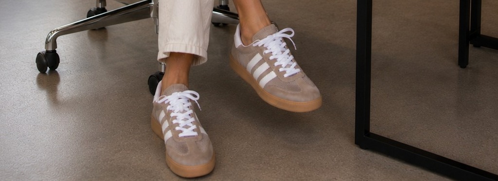 Zapatillas Soho gris bajo escritorio en piso pulido, contexto editorial oficina