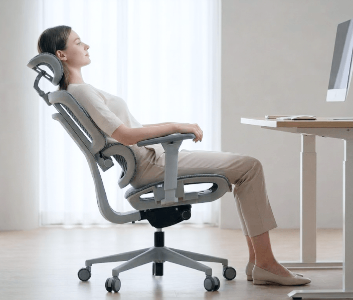 Mulher relaxando reclinada na cadeira ergonômica DT3 Selene em ambiente de home office.