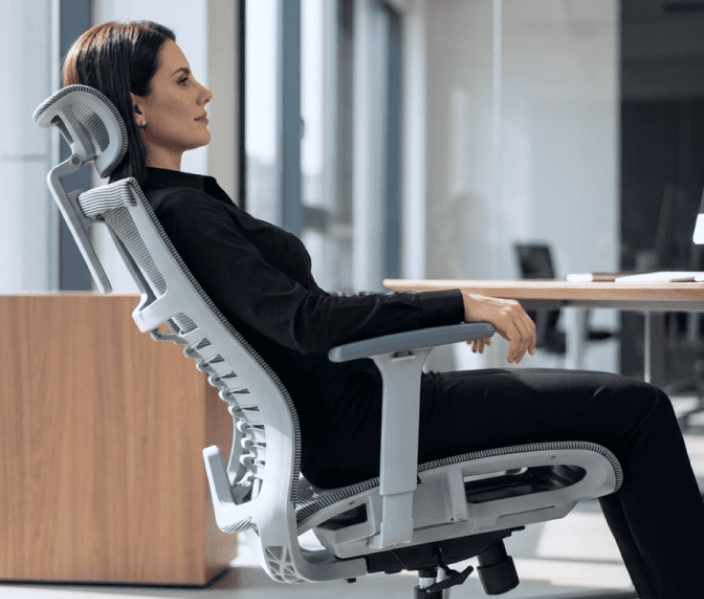 Mulher reclinada na cadeira ergonômica DT3 Saros em ambiente de escritório moderno.