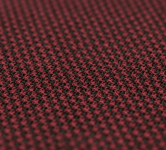 Close-up do Têxtil Cashmere HY em tom vinho e preto com trama em xadrez miúdo (houndstooth). À esquerda, o texto destaca que a cor e a textura são preservadas mesmo após o uso diário.