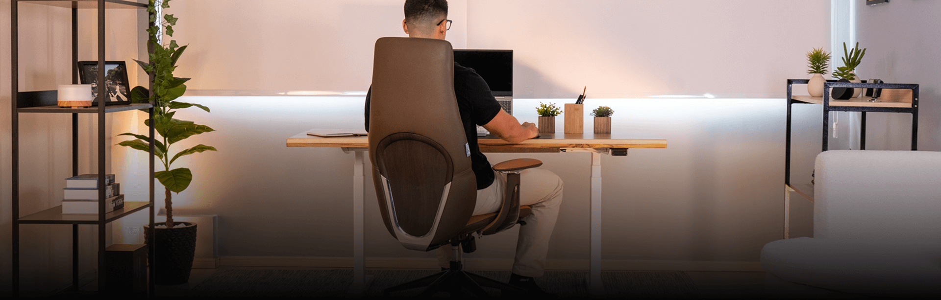 Mesa com regulagem de altura F50 em altura de uso convencional, ambientada com modelo masculino. Visão fotográfica frontal