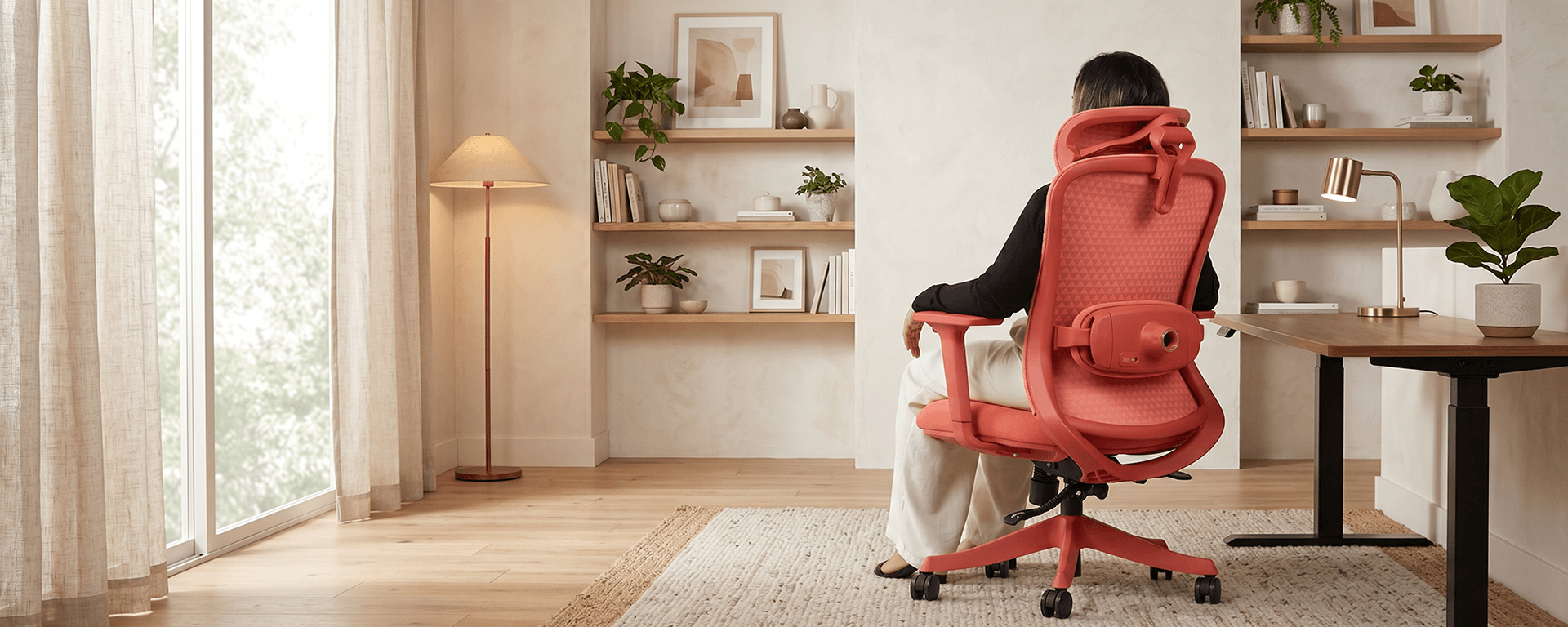 Vista traseira de uma mulher sentada na cadeira ergonômica Atria DT3, destacando o massageador lombar Relax integrado em um ambiente de home office elegante.