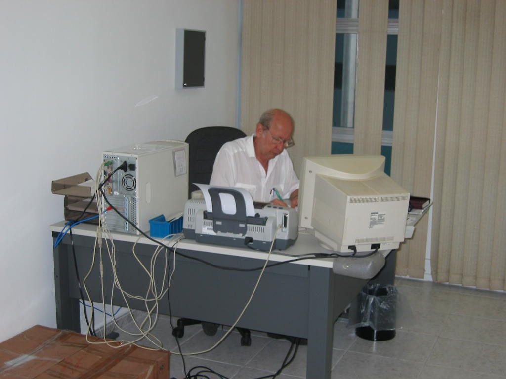 Registro histórico de uma pessoa trabalhando em uma mesa com computador e equipamentos.