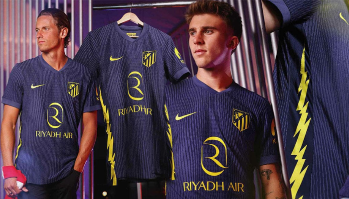 Camisa reserva do Atlético de Madrid Nike 2025-2026 em azul marinho com detalhes amarelo neon, com raios nas laterais e gola V estilizada.