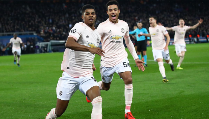 Camisa titular retrô do Manchester United da temporada 2018-2019, nas cores rosa e laranja. A camisa apresenta o logo da Adidas e o escudo do clube. É possível ver detalhes do design inspirado na época em que Ole Gunnar Solskjær assumiu o comando da equipe, incluindo referências à histórica virada contra o PSG