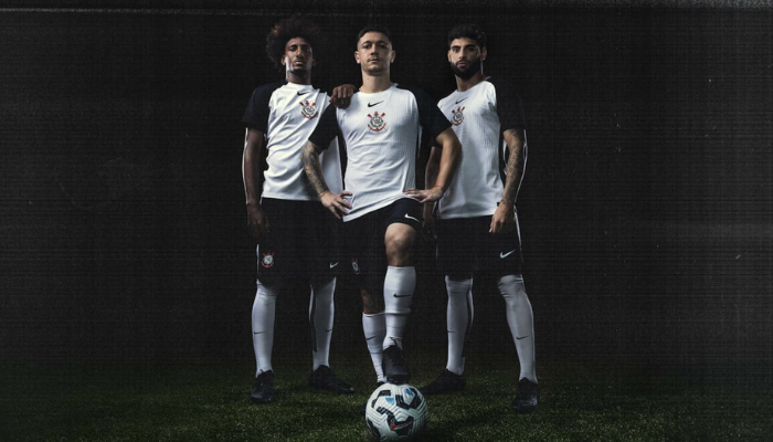 Camisa titular do Corinthians 2025-2026, branca com detalhes em preto, destacando o escudo e a frase "Todo Poderoso Timão" na gola.
