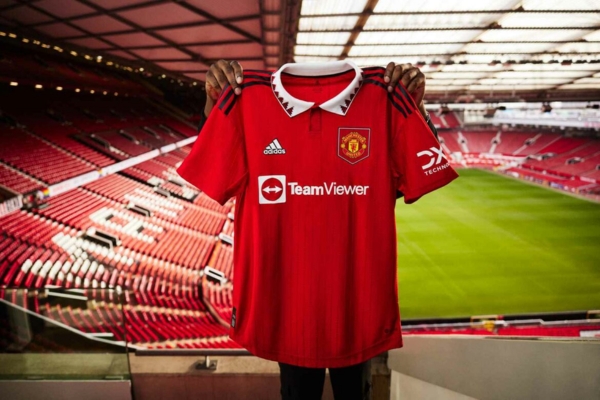 Camisa Titular do Manchester United Adidas 2022/23 em vermelho, branco e preto, com gola p&oacute;lo, tr&ecirc;s listras nos ombros e detalhes inspirados na Copa de 1994.