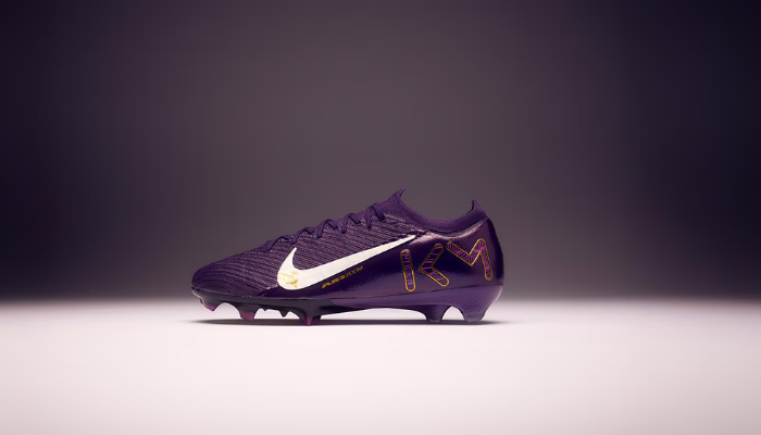 Chuteiras Nike Air Zoom Mercurial Vapor 16 Elite FG x Mbappé em roxo, branco e dourado, destacando seu design dinâmico e elementos inspirados na carreira de Kylian Mbappé.
