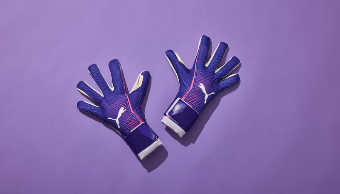 Luva de Goleiro Puma Ultra Ultimate Hybrid nas cores azul, branca e rosa, com dorso flexível e elementos de silicone para maior controle. Palma com látex 4mm Superior Grip para aderência em qualquer clima, corte híbrido para ajuste confortável e punho elástico com cinta de fechamento seguro. Modelo profissional usado por grandes goleiros.