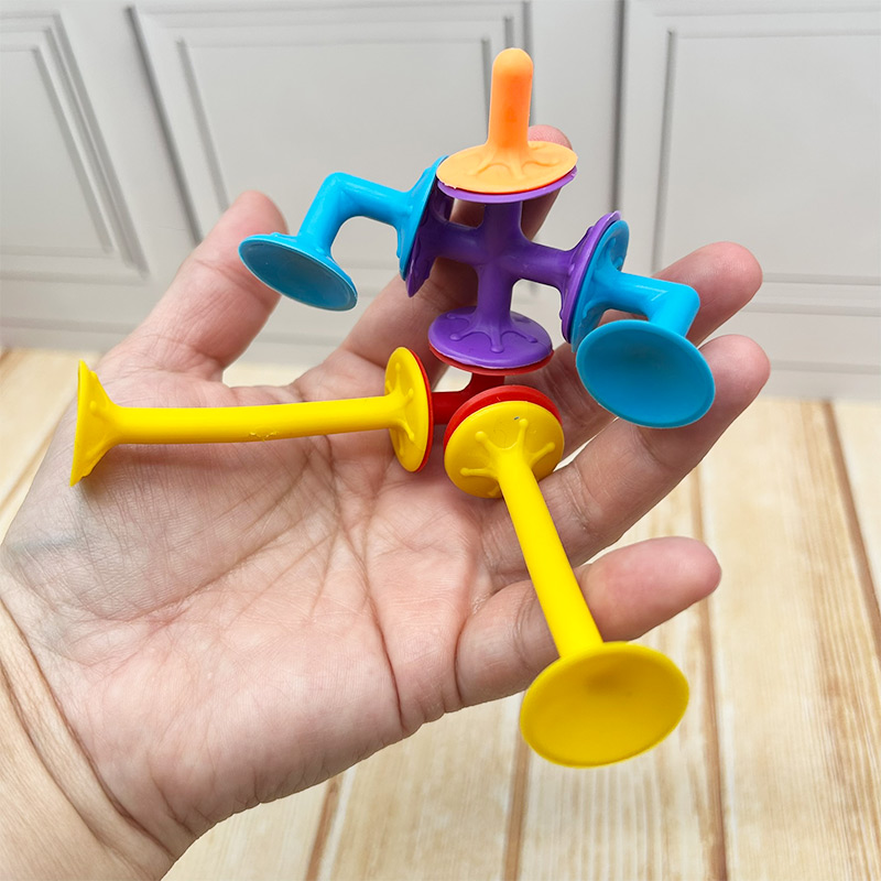 Mano sosteniendo una construcción hecha con sopapas PopFun de colores