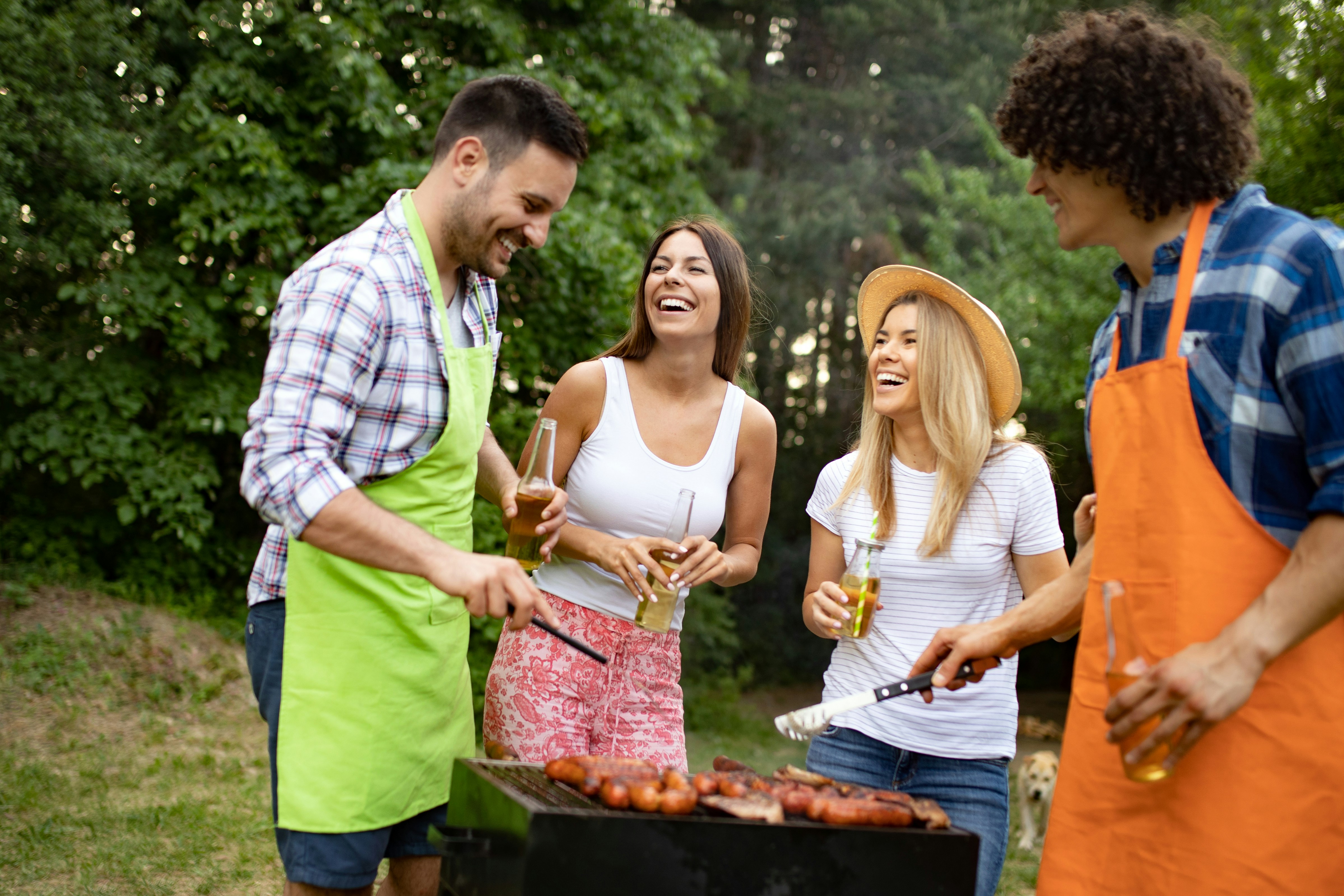 Grupo de amigos disfrutando de un asado al aire libre, entre risas, bebidas y buena onda en un ambiente relajado y natural.