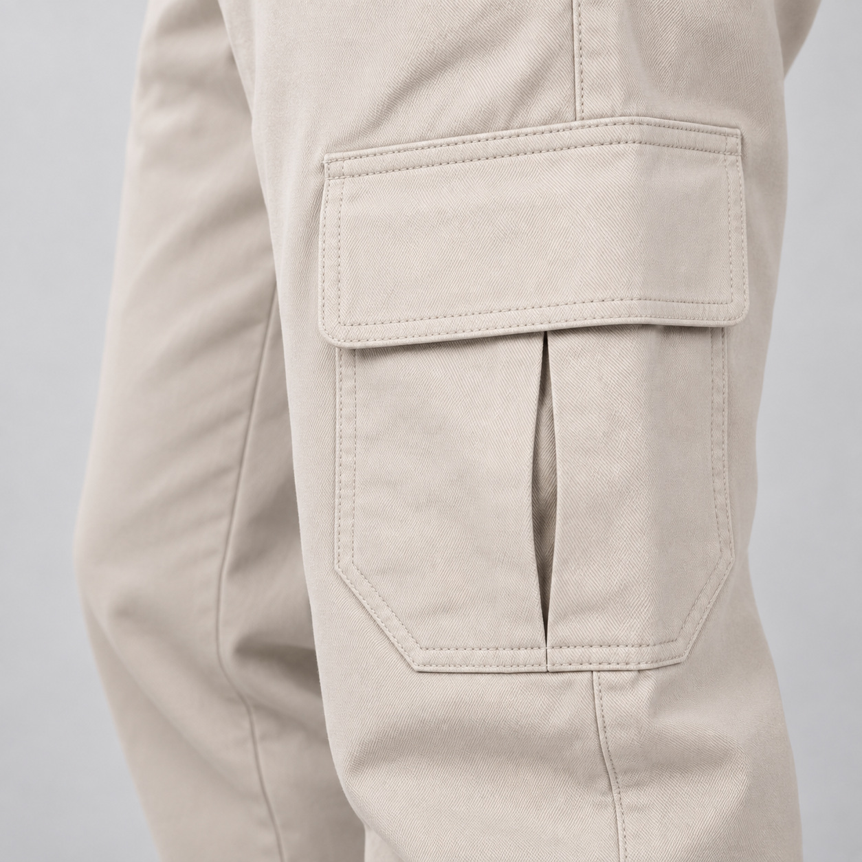 Bolso cargo lateral com aba e prega central em sarja bege claro.