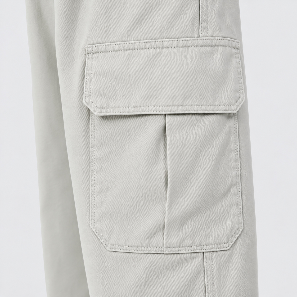 Bolso cargo com aba, costuras aparentes e textura da sarja bege clara.