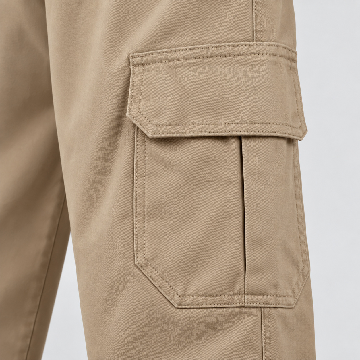 Bolso cargo com aba, costuras aparentes e textura da sarja bege.