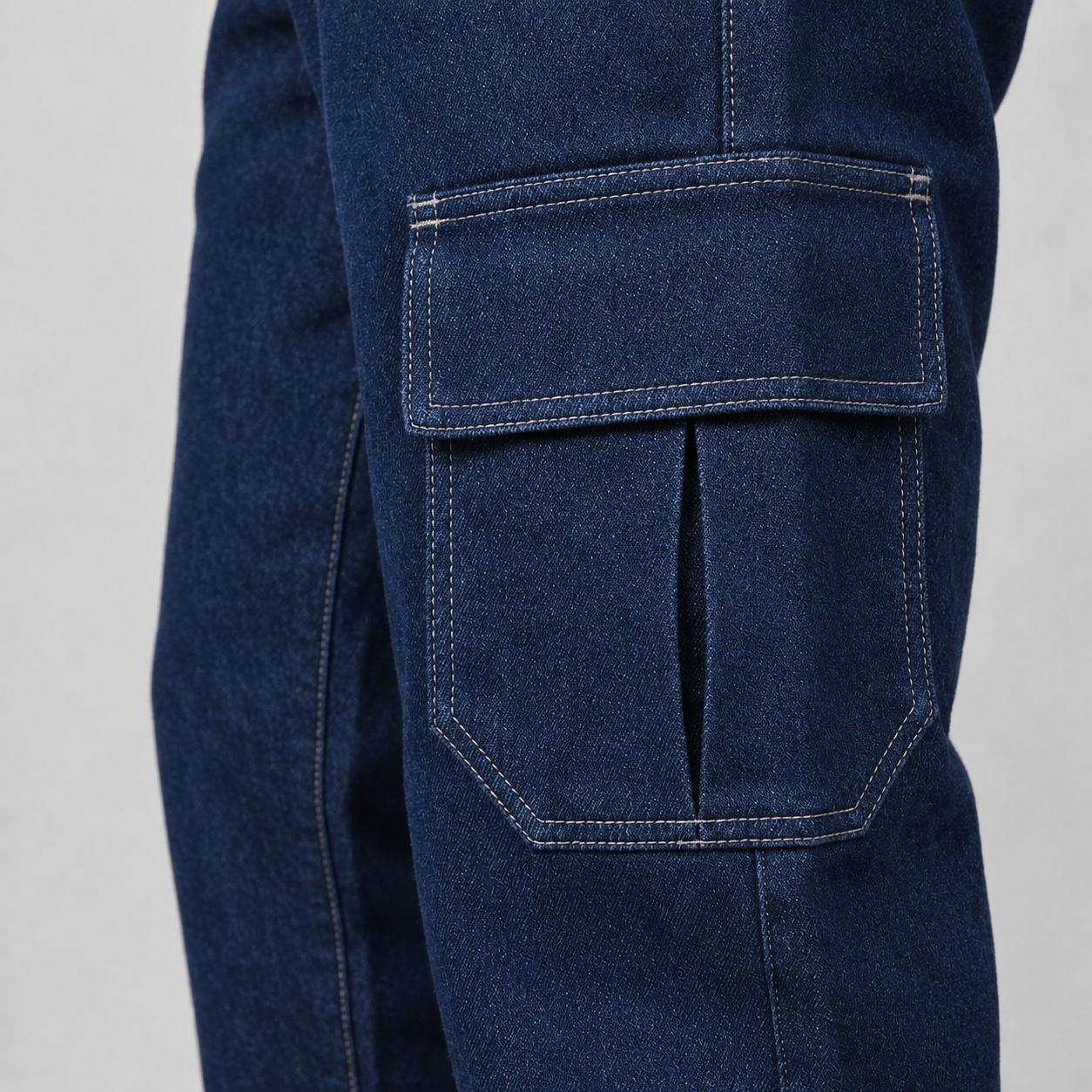 Bolso cargo com aba, costuras aparentes e textura do jeans azul-escuro.