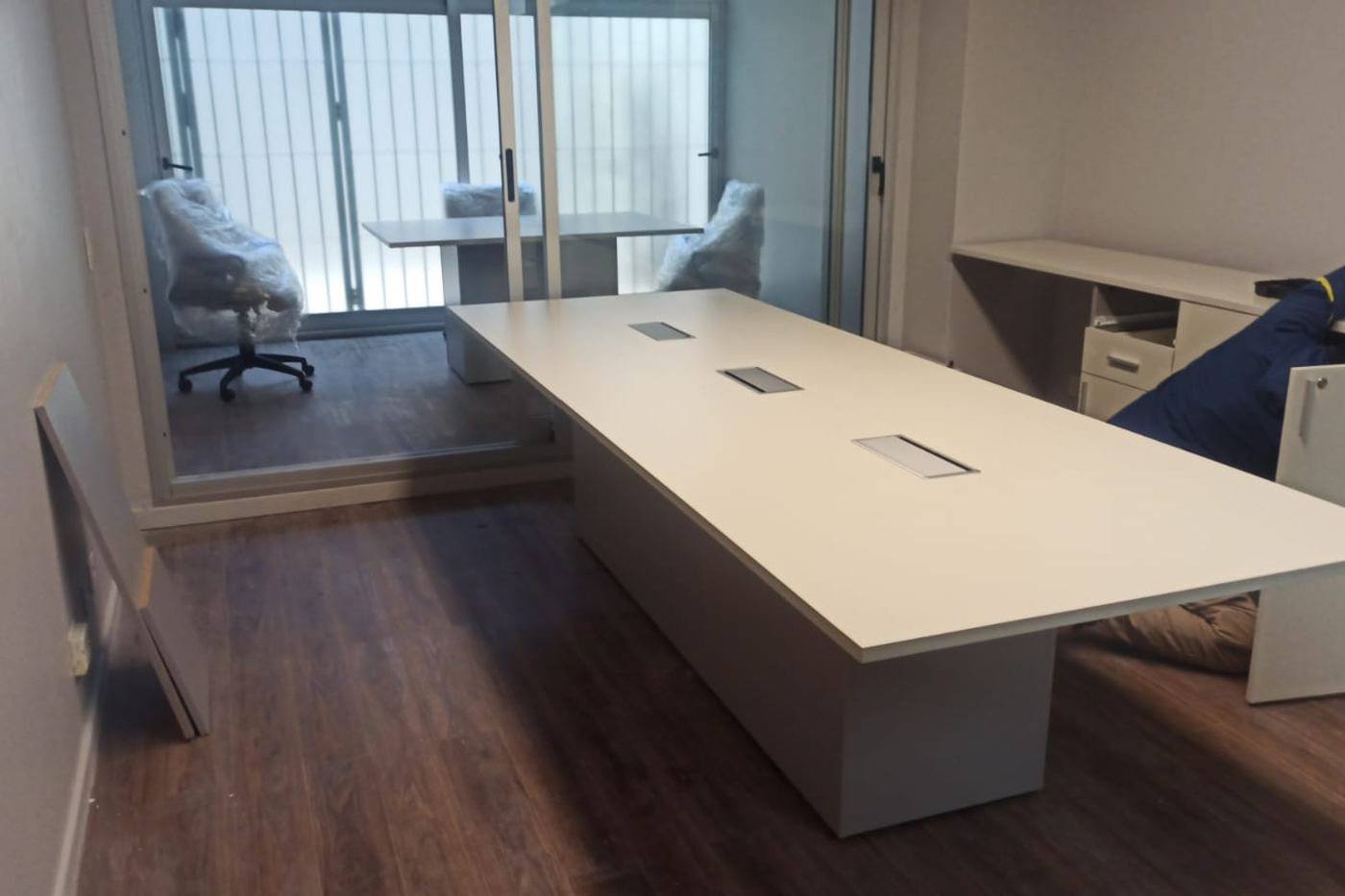 Sala de reunión corporativa con mesa de melamina y pasacables integrados