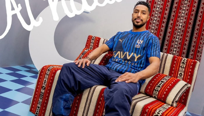 Camisa Al Hilal 2025 azul royal com listras em estilo giz, meia-lua estilizada, detalhes dourados, escudo e logos em dourado, collab com KidSuper e PUMA
