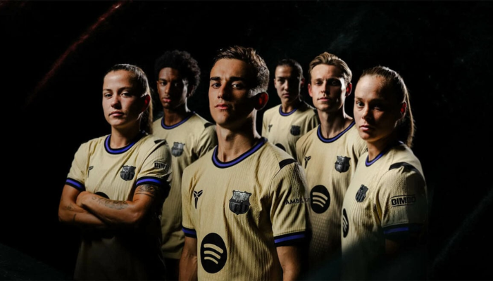 Camisa reserva Barcelona 2025/26 dourada com detalhes violeta e preto, escudo com logotipo Kobe Sheath em textura Black Mamba.