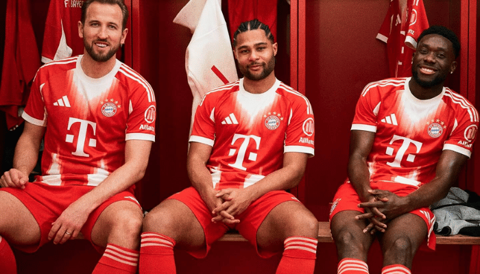 Camisa titular Bayern 2025 vermelha com gola branca, detalhes brancos nos punhos, escudo tradicional à esquerda, “Mia San Mia” na nuca, e logo da Adidas em branco no lado direito