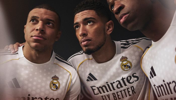 Camisa titular Real Madrid 2025/26 branca com jacquard circular, detalhes amarelos e cinzas, três listras pretas nos ombros, escudo oficial no peito e logo Adidas em preto