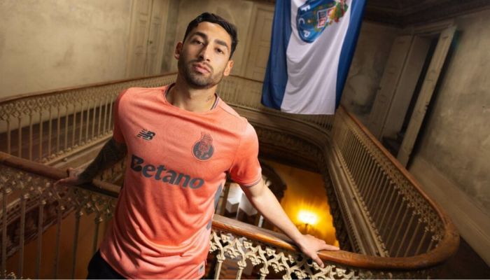 Camisa reserva do FC Porto 2025/26 na cor salmão com estampa floral de camélias, gola redonda com friso cinza, escudo e logos em cinza e selo “Aniversár10” dentro da gola