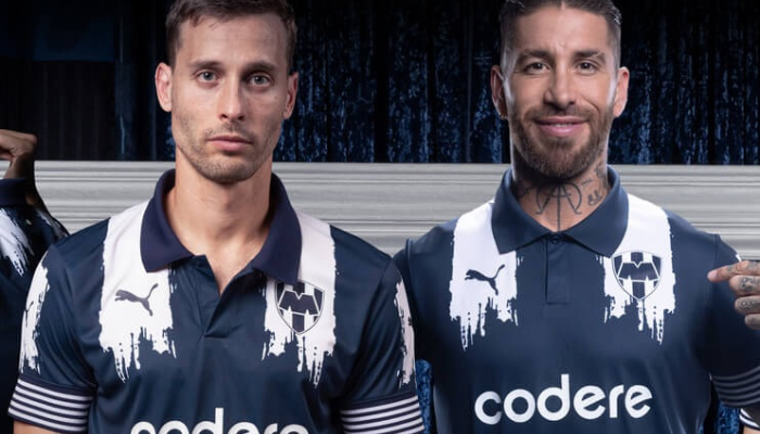 Camisa titular Monterrey 2025 azul marinho com listras brancas pinceladas, gola polo azul, punhos listrados, escudo atual no peito, detalhe da bandeira mexicana na nuca e versão especial 80 anos.