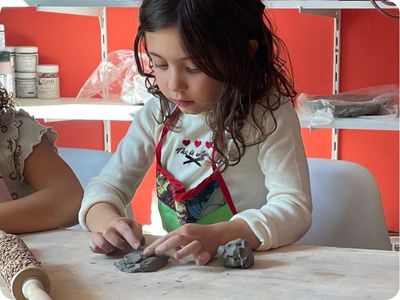 Menina modelando argila com os dedos
