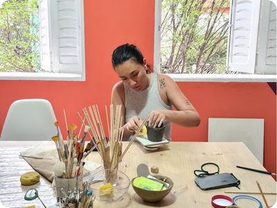 Aluna modelando peça em argila durante aula de cerâmica no ateliê Shoyu Crafts
