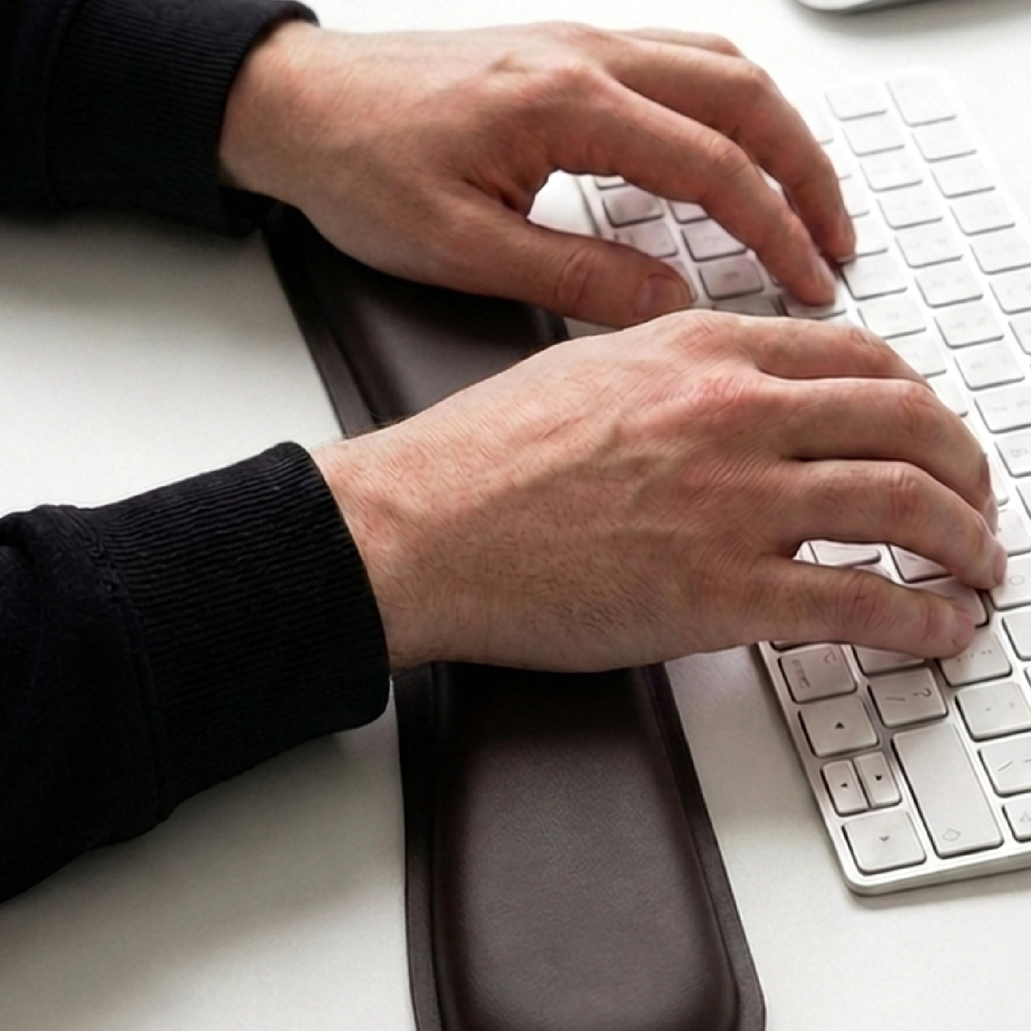 Manos tipeando en un teclado con el apoyamuñecas largo del kit Zentra delante