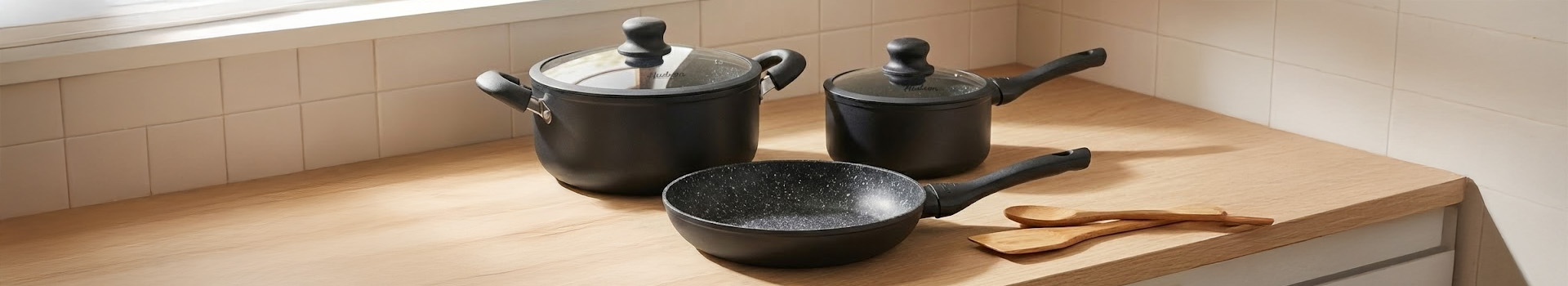 3 ollas de granito negras sobre una mesada de madera