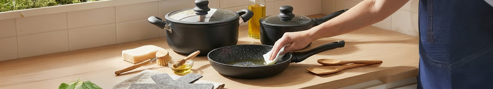 Mano aplicando aceite en una olla de granito para curarla