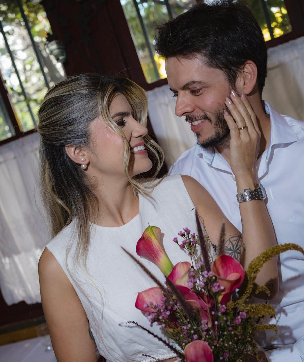 Bruna e Lucas no dia do casamento, com buquê de copos-de-leite