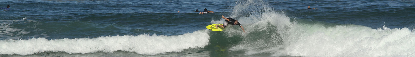 Surfista manobra em onda no mar com prancha amarela, representando o estilo de vida Tubástico e a conexão entre surf, liberdade e natureza.