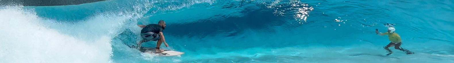 Surfista entuba em onda cristalina azul, exibindo adrenalina e a beleza do surf em cenário paradisíaco.
