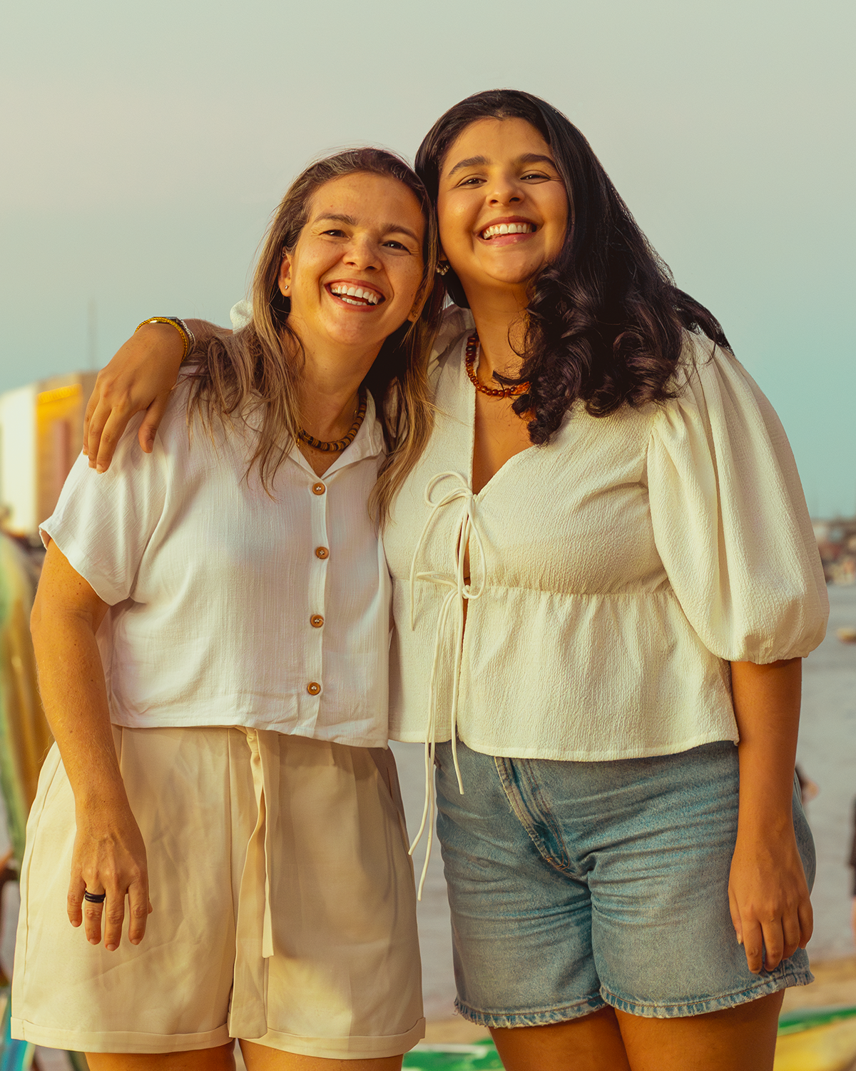 Juliana, filha, e Julia, mãe, criadoras da marca Maria Fulô Acessórios, estão lado a lado sorrindo.