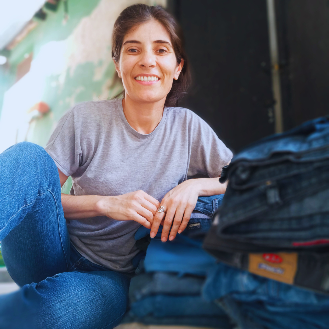 modista sentada junto a pila de jeans