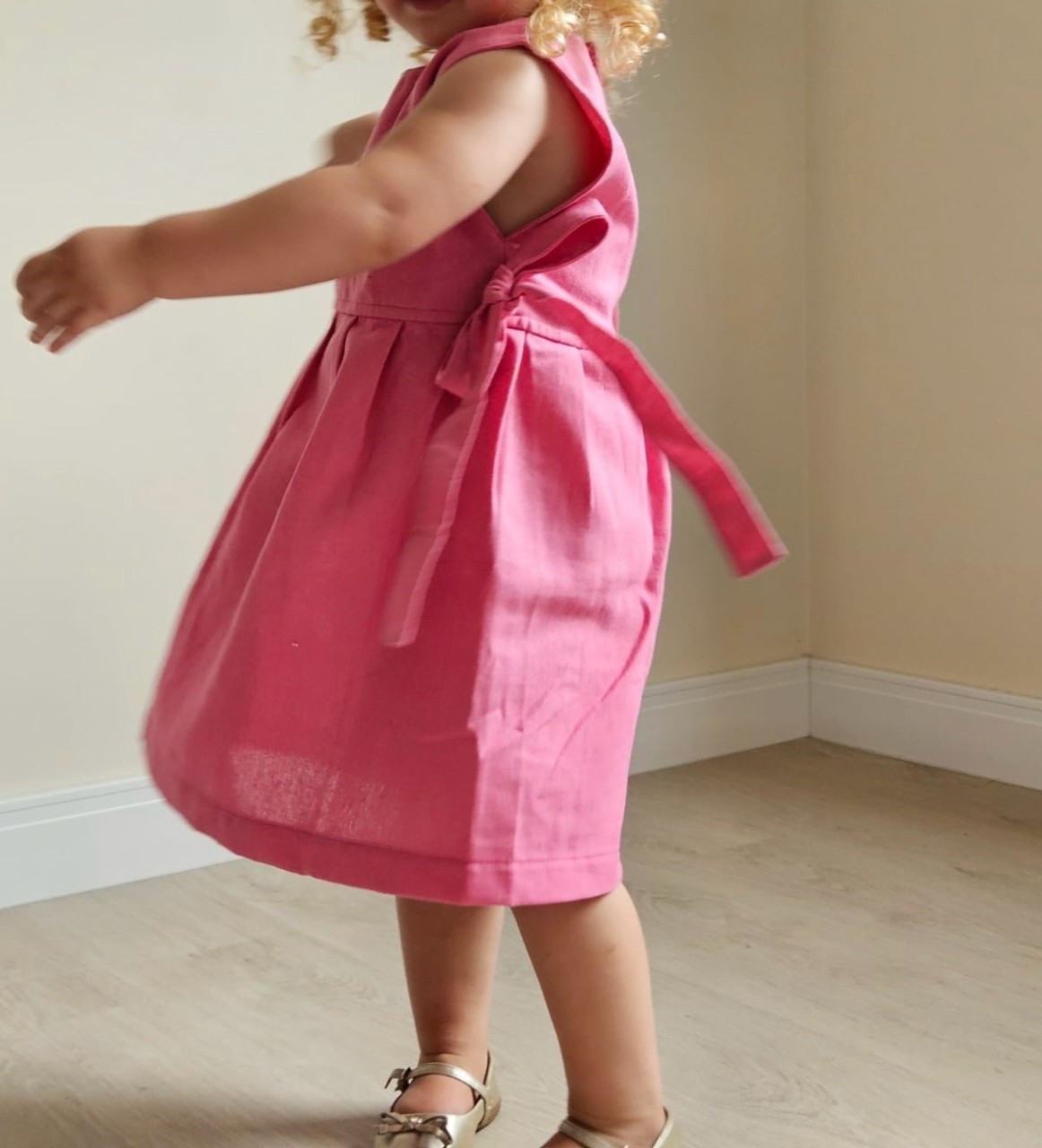 Uma menina usando um vestido linho misto dançando feliz