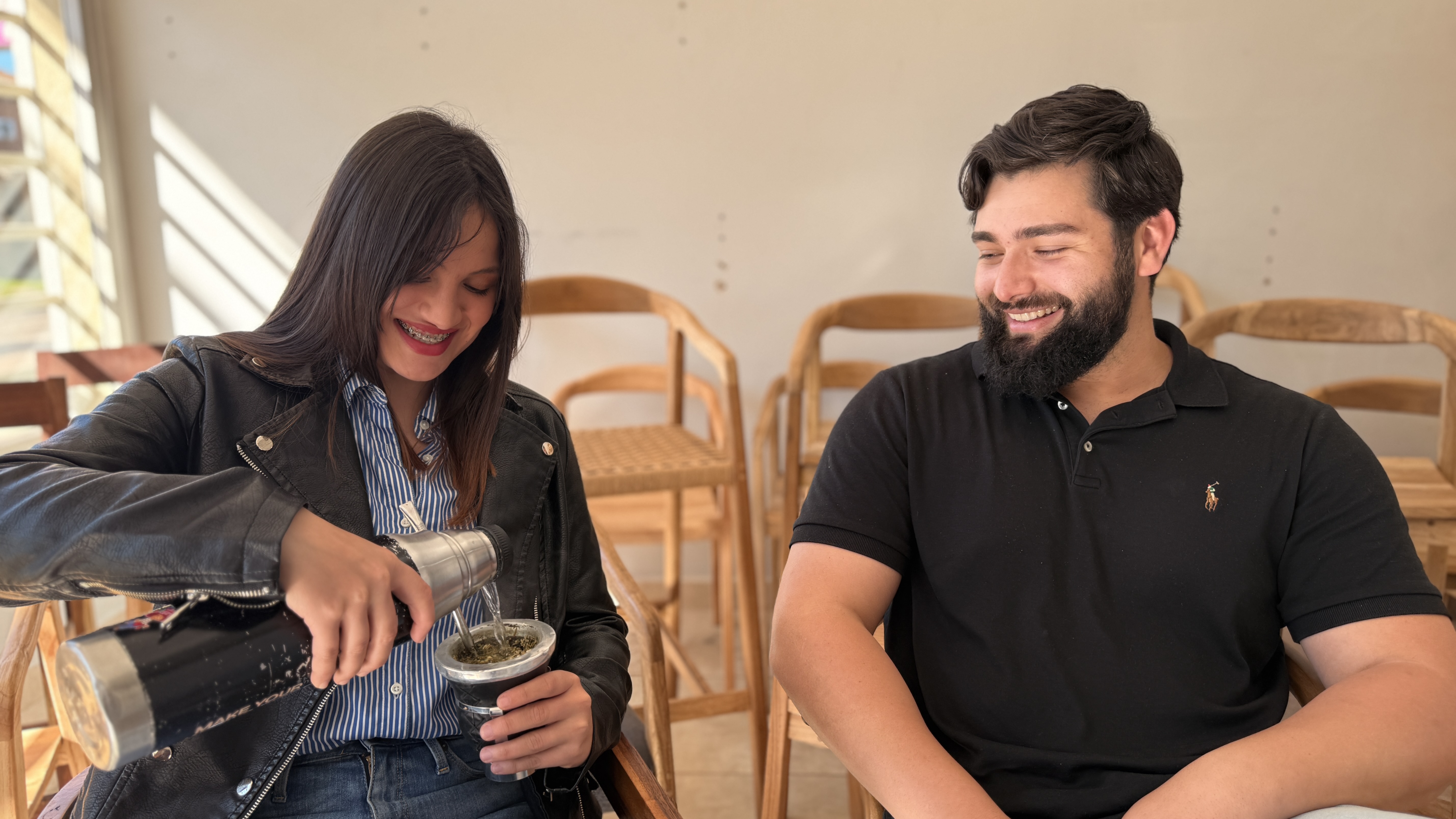Cinthia y Franco sonrientes y tomando mates sentados uno al lado del otro rodeados de muebles