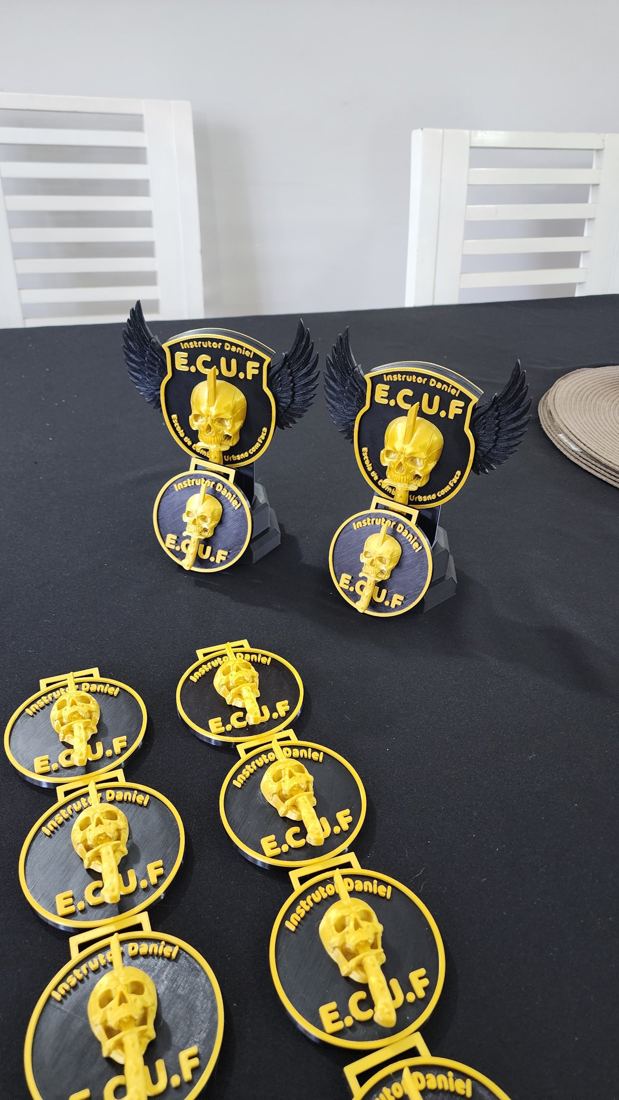 Troféus e medalhas pretos e dourados da E.C.U.F com caveira em relevo e asas