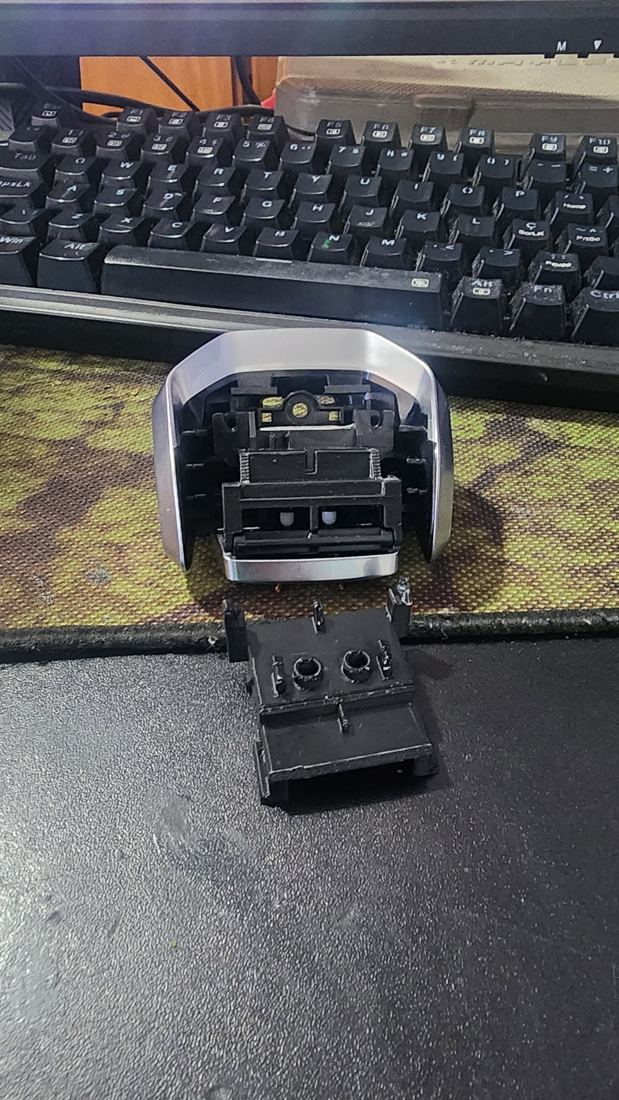 Manopla de câmbio automático do Jaguar aberta, com a peça de apoio do botão recriada em impressão 3D à frente