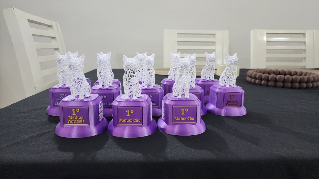 Troféus roxos com escultura vazada de cão branco e placas como 1º Melhor Fantasia, 1º Menor Cão e 1º Maior Cão