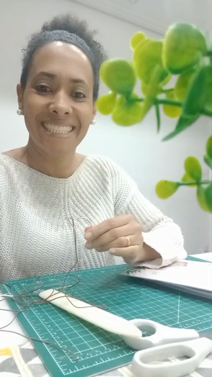 Érica, fundadora da Criarte Gifts, costurando um caderno à mão no ateliê