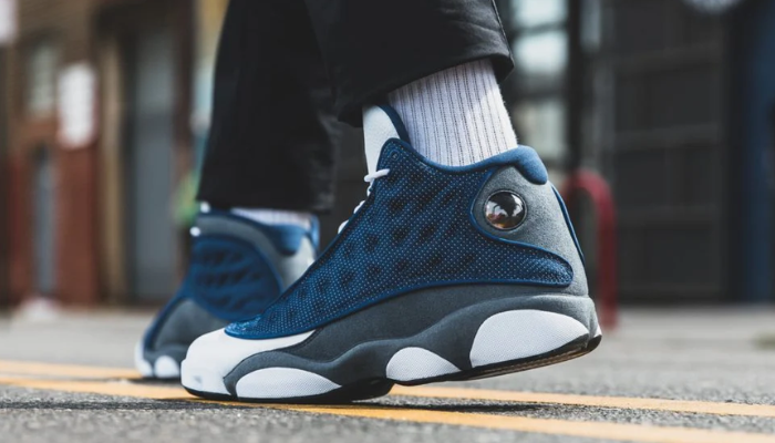 Tênis Air Jordan 13 Retro Flint azul e cinza com detalhes reflexivos e sola holográfica.