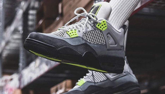 Tênis Air Jordan 4 Retro 95' Neon em tons de cinza com detalhes em neon e logo Nike refletivo.